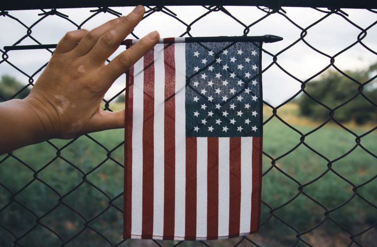Mano sosteniendo la bandera de Estados Unidos, aumentan las deportaciones en 6 meses.