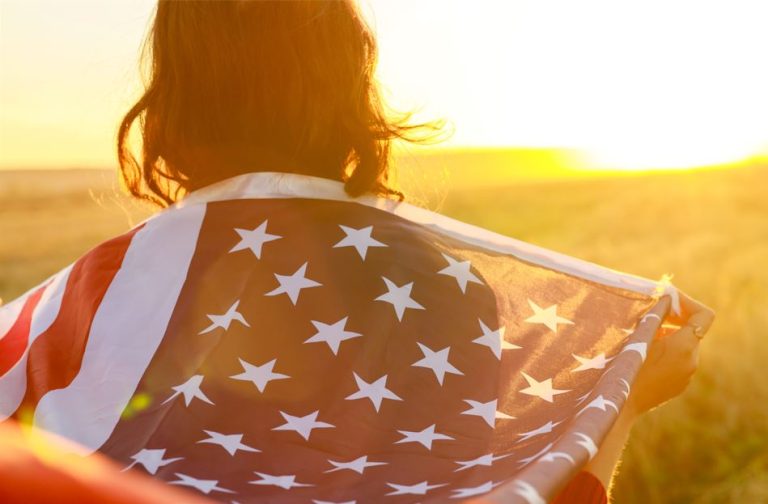 Latina luce la bandera de Estados Unidos sobre sus hombros esperanzada por el Estatus de Proteccion Temporal